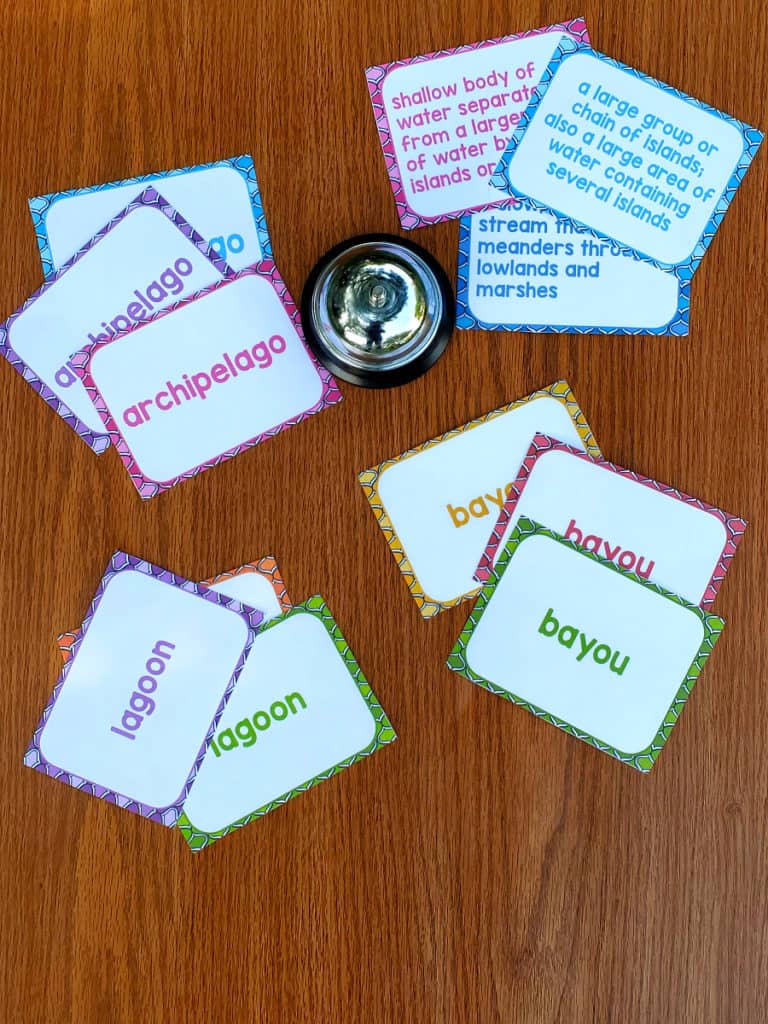 clue cards and vocabulary word cards on a table with a bell